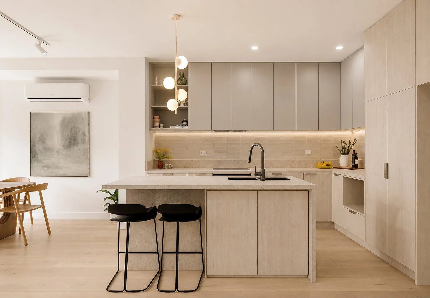 Modern kitchen with light wood cabinets, a kitchen island with black bar stools, and minimalist decor.