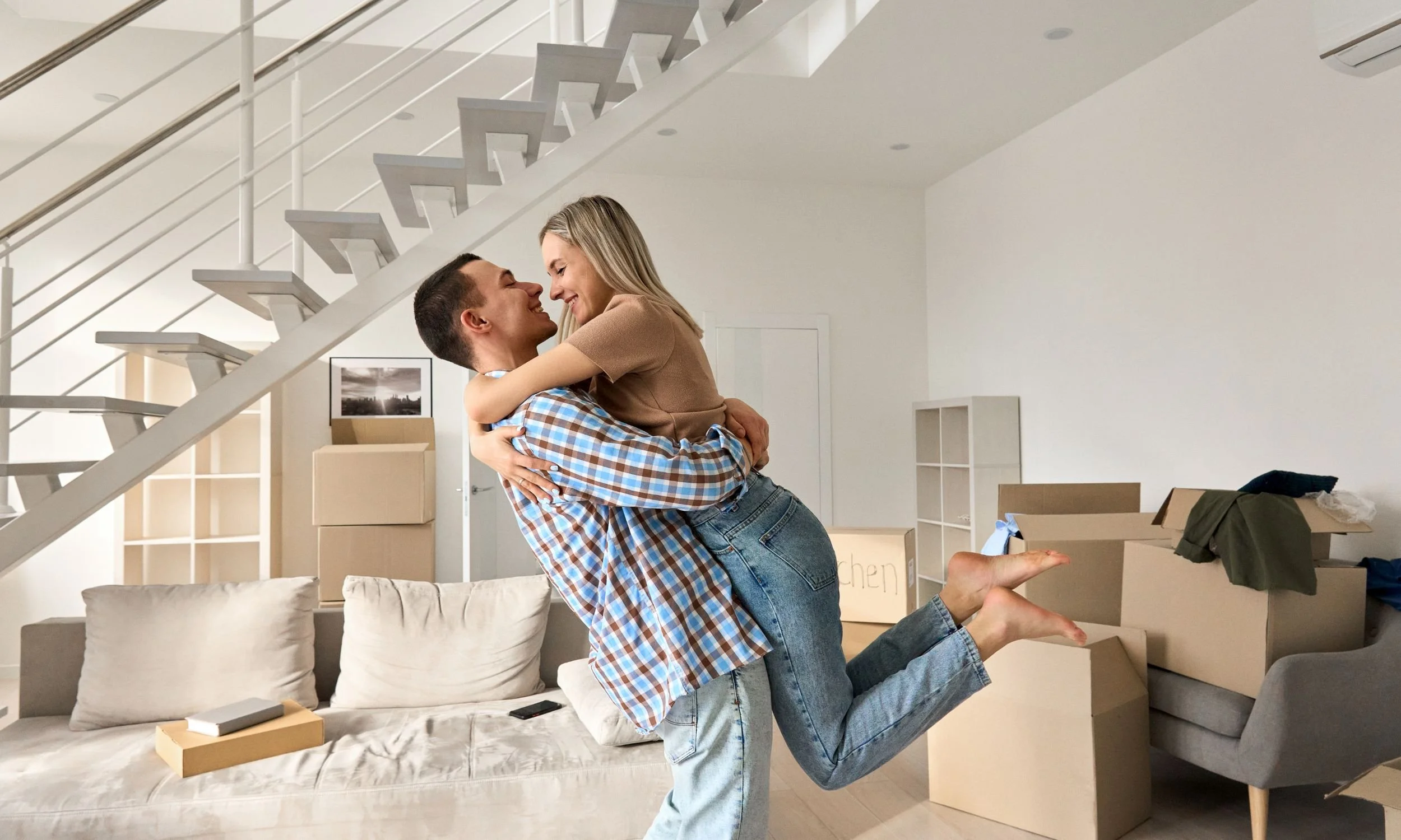 Couple hugging in new home with moving boxes after divorce