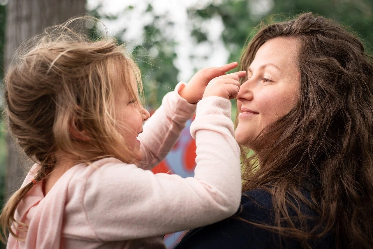 Smiling mother holding daughter while playing together, symbolizing the positive impact of mediation in protecting children’s well-being during family law disputes.