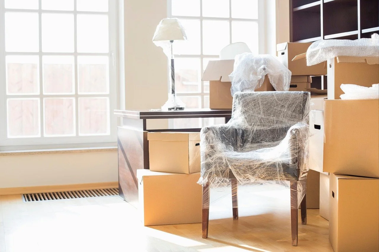Packed boxes and wrapped furniture in an empty home, symbolizing relocation and its impact on child custody decisions in New Jersey.