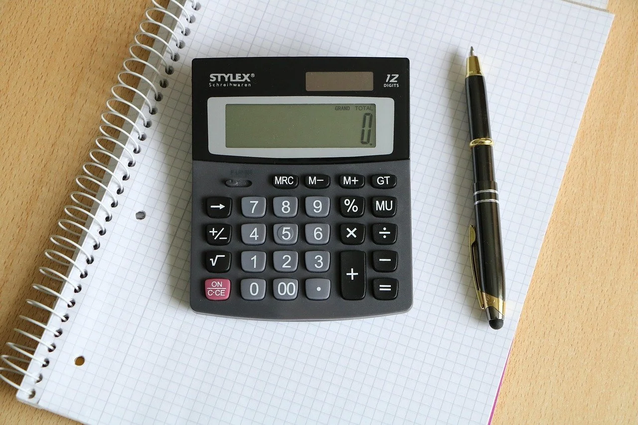 Calculator and pen on a notebook, representing financial planning and property division during a New Jersey divorce.