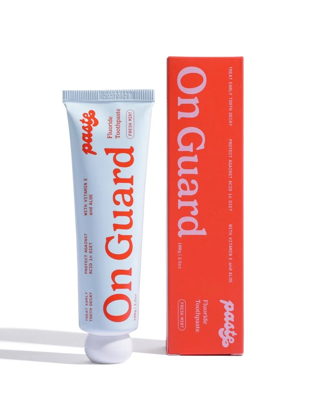 A tube of mint fluoride toothpaste next to its corresponding box.