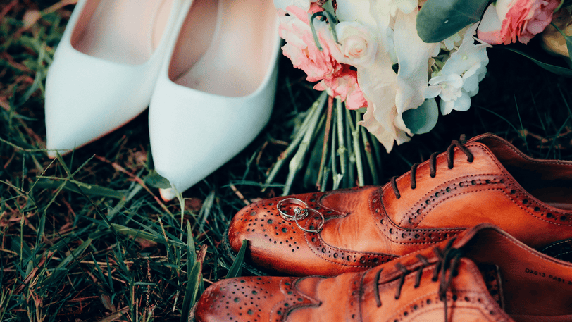 A pair of men’s and women’s dress shoes, two rings, and a bouquet.