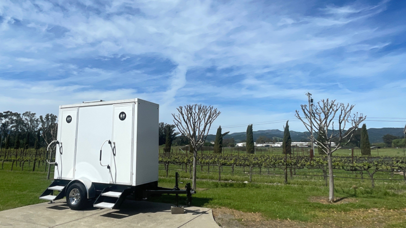 A luxury portable toilet stationed in a rural vineyard venue for an event.