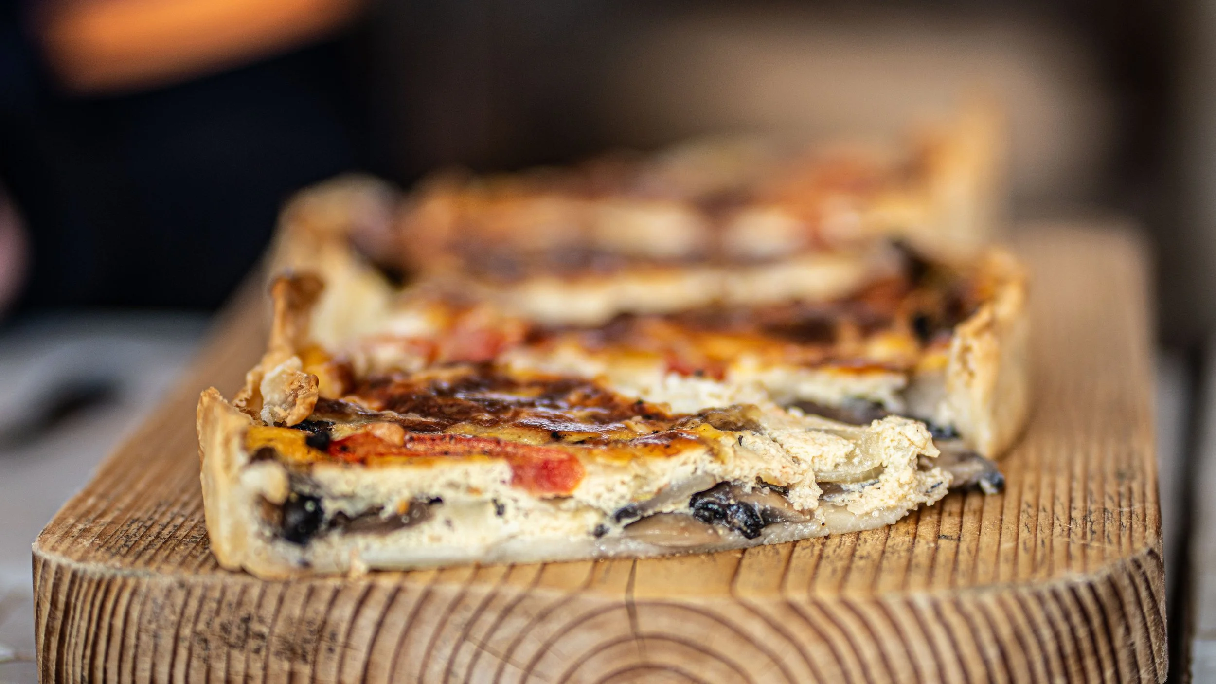 Slices of mushroom and cheese pizza on a wooden cutting board.