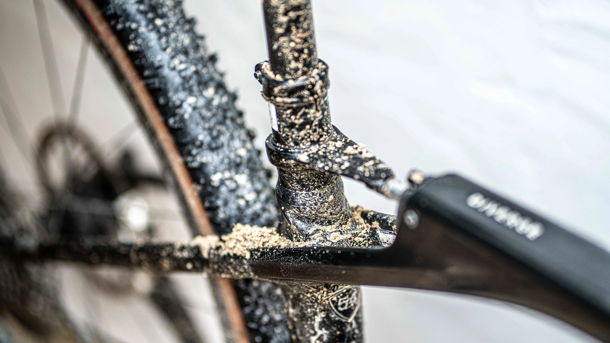 Close-up of a mountain bike's crankset and chainring, covered in dirt and mud, showing the chain and part of the frame.