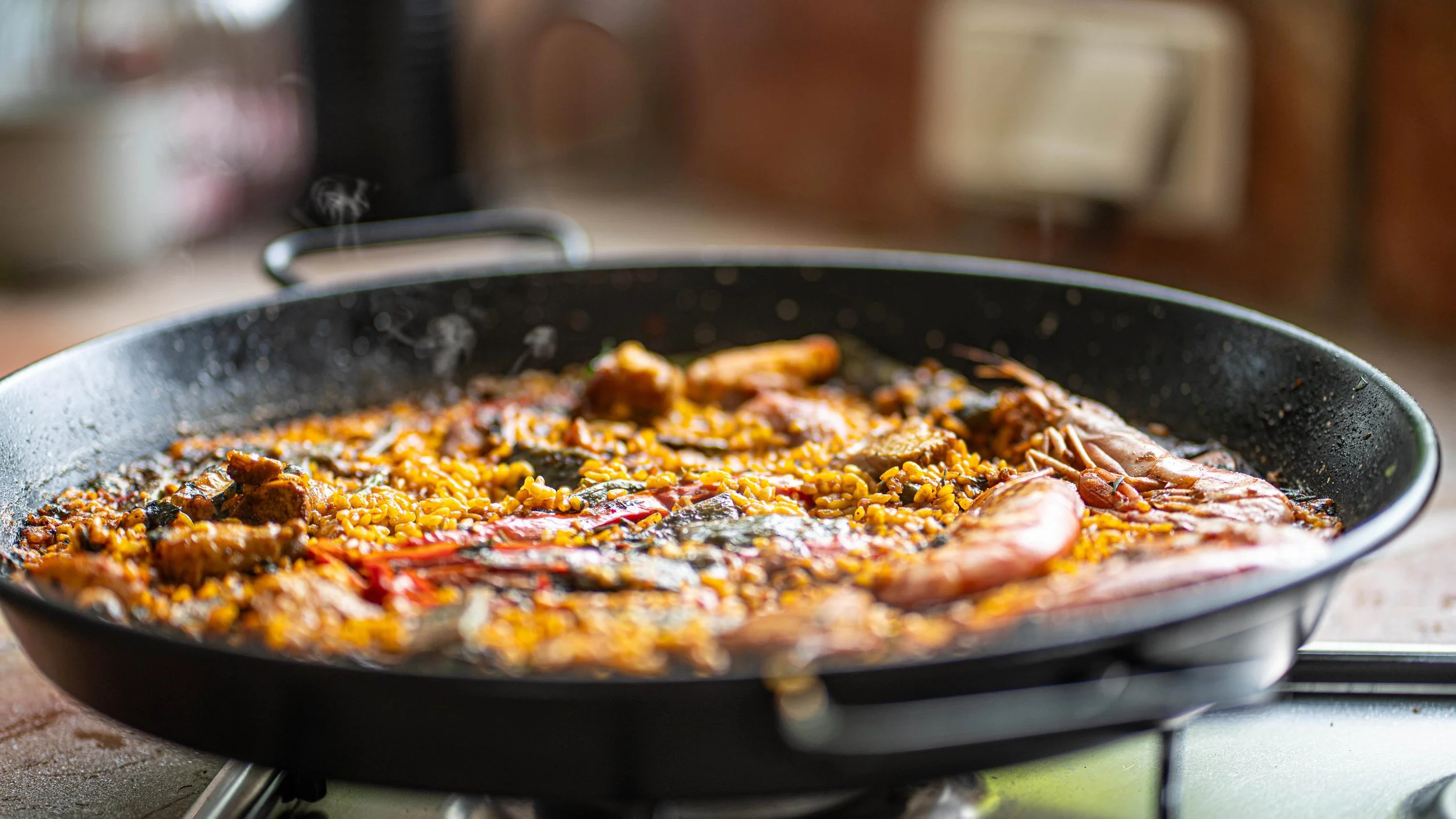 Pan filled with cooked seafood and rice dish, including shrimp and vegetables