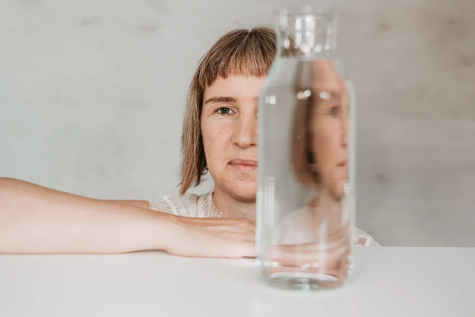 Vrouw met een waterfles die haar reflectie toont, symboliseert helderheid en focus in webstrategie.