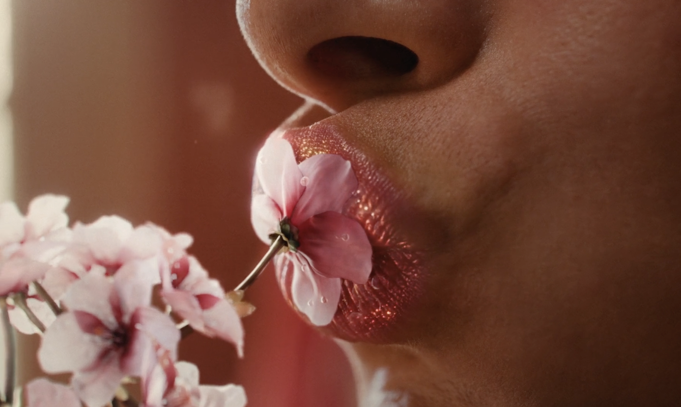 Close-up of a woman touching a flower to her lips in a Burt’s Bees campaign, cinematography by Johan-Fredrik Bødtker.