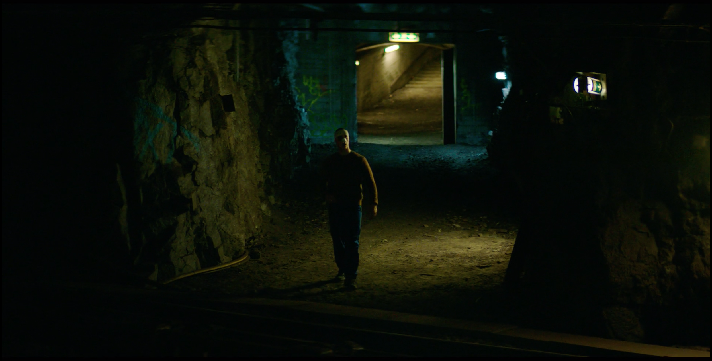 Man standing in a dark underground tunnel in Valkyrien, cinematography by Johan-Fredrik Bødtker.