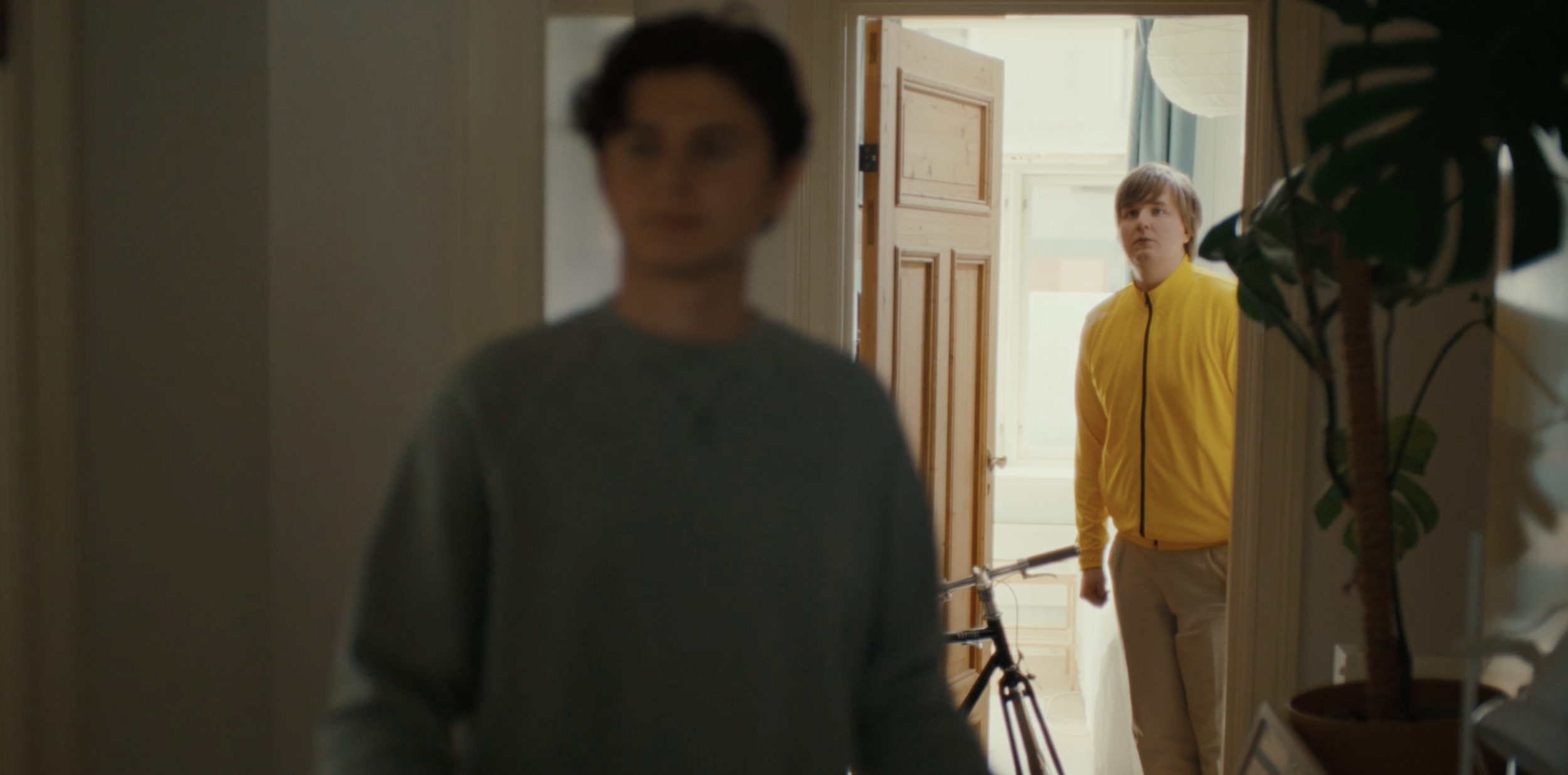 Man in a yellow jacket standing in a doorway in an Ice commercial, cinematography by Johan-Fredrik Bødtker.