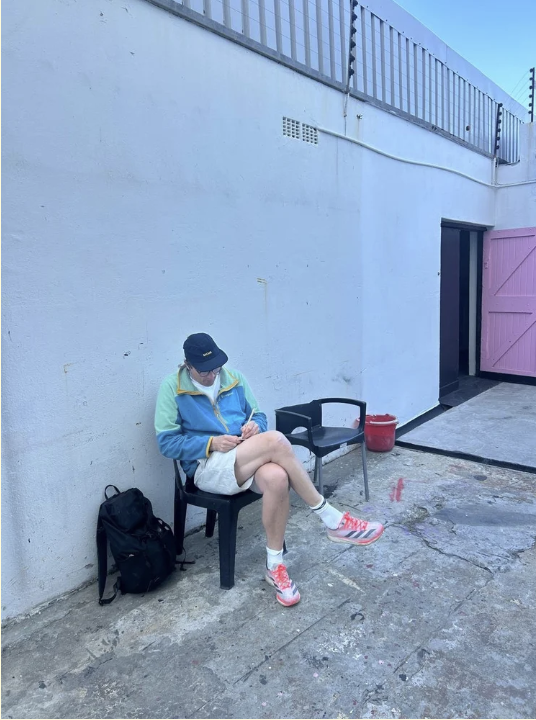 Cinematographer Johan-Fredrik Bødtker sitting outside in colourful sportswear against a graphic pink and white wall.