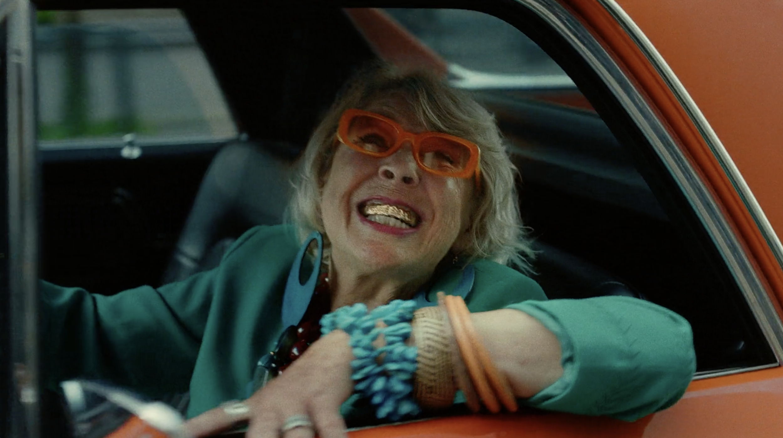 Woman wearing orange glasses leaning out of a car in a Power commercial, cinematography by Johan-Fredrik Bødtker.