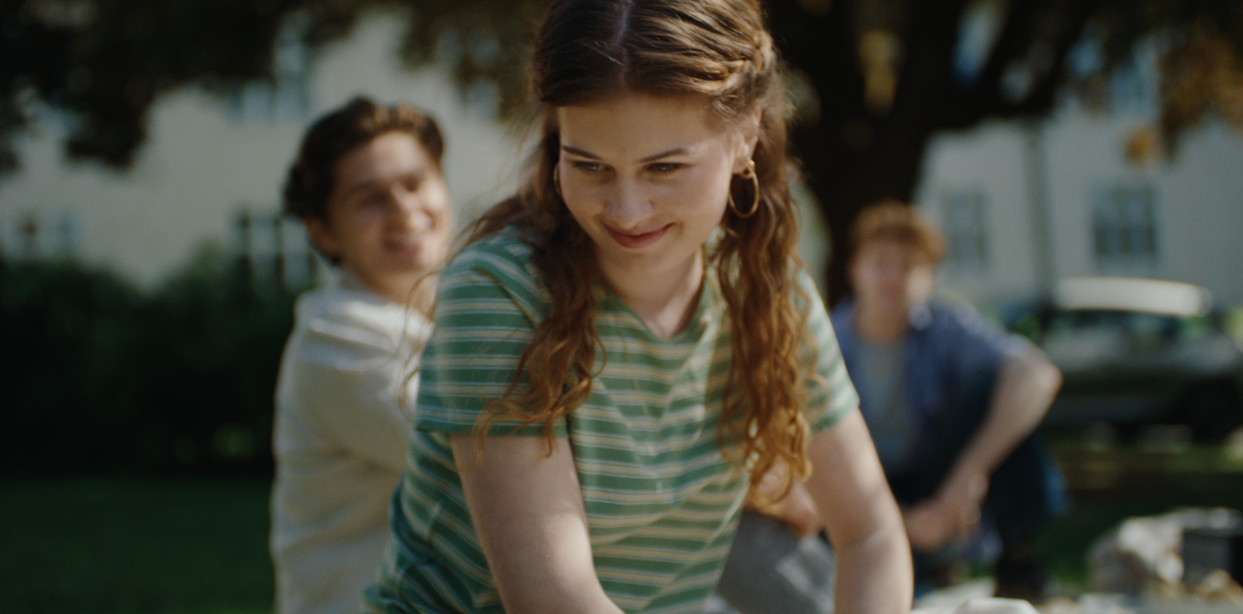Young woman outdoors with two people behind her in an Ice commercial, cinematography by Johan-Fredrik Bødtker.