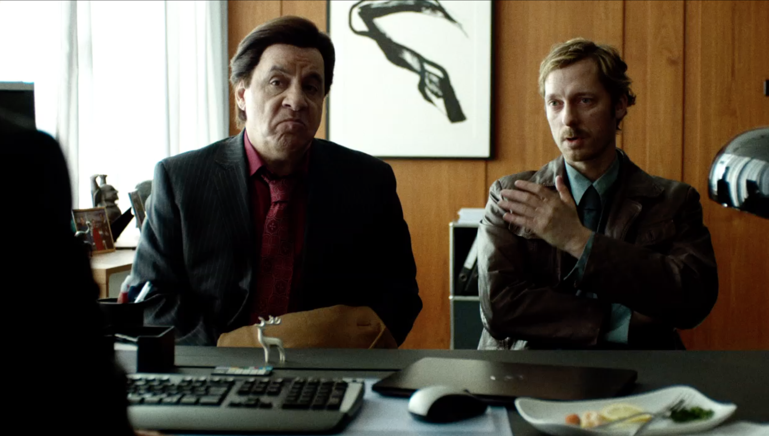 Two steven van zandt trond fausa aurvågmen seated at a desk in an office scene from Lilyhammer, cinematography by Johan-Fredrik Bødtker.