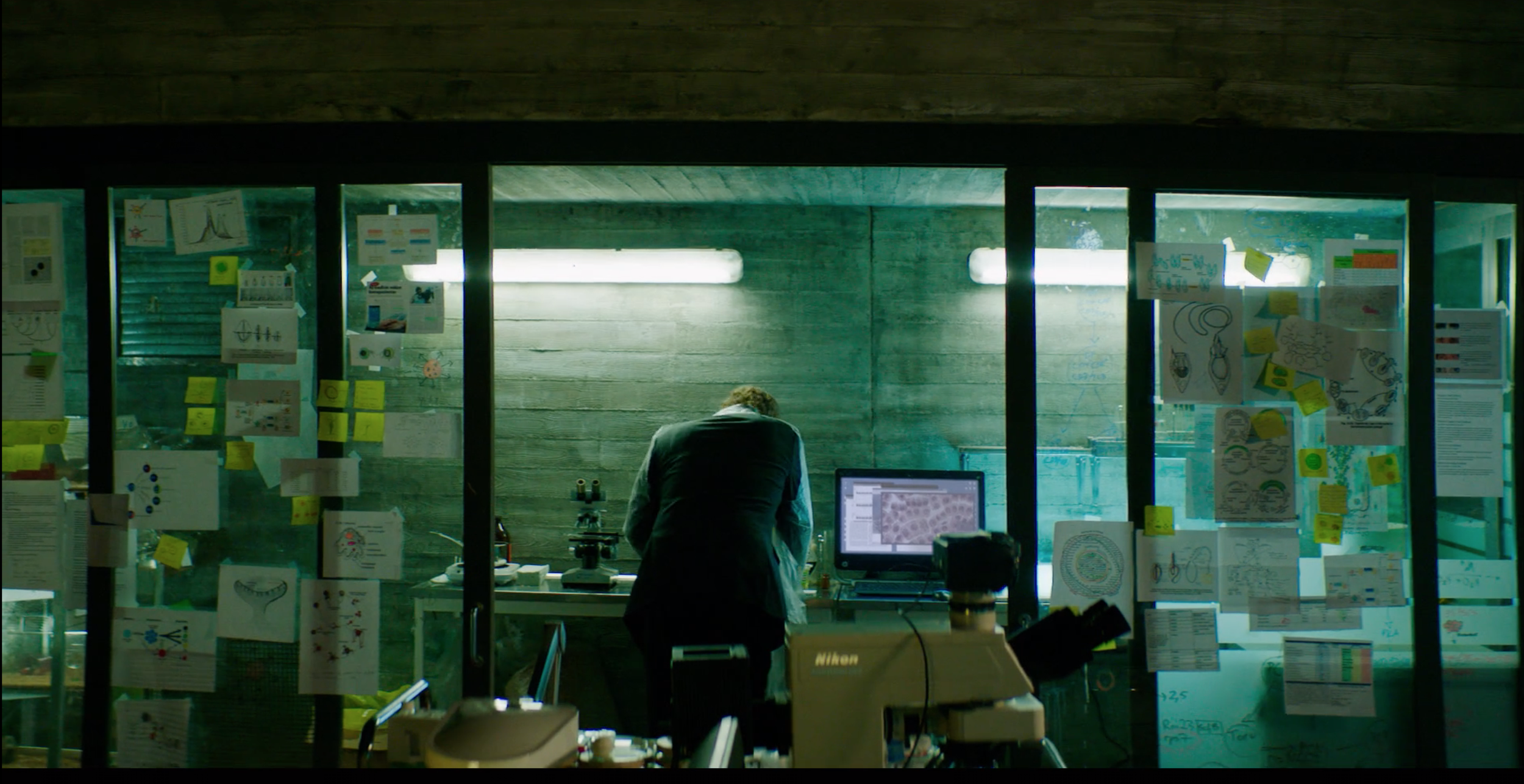 Person working inside a glass-walled room above the city in Valkyrien, cinematography by Johan-Fredrik Bødtker.