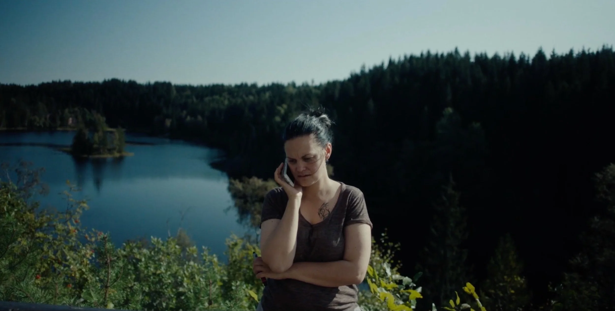 Woman standing by a lake surrounded by forest in Fenris, cinematography by Johan-Fredrik Bødtker.