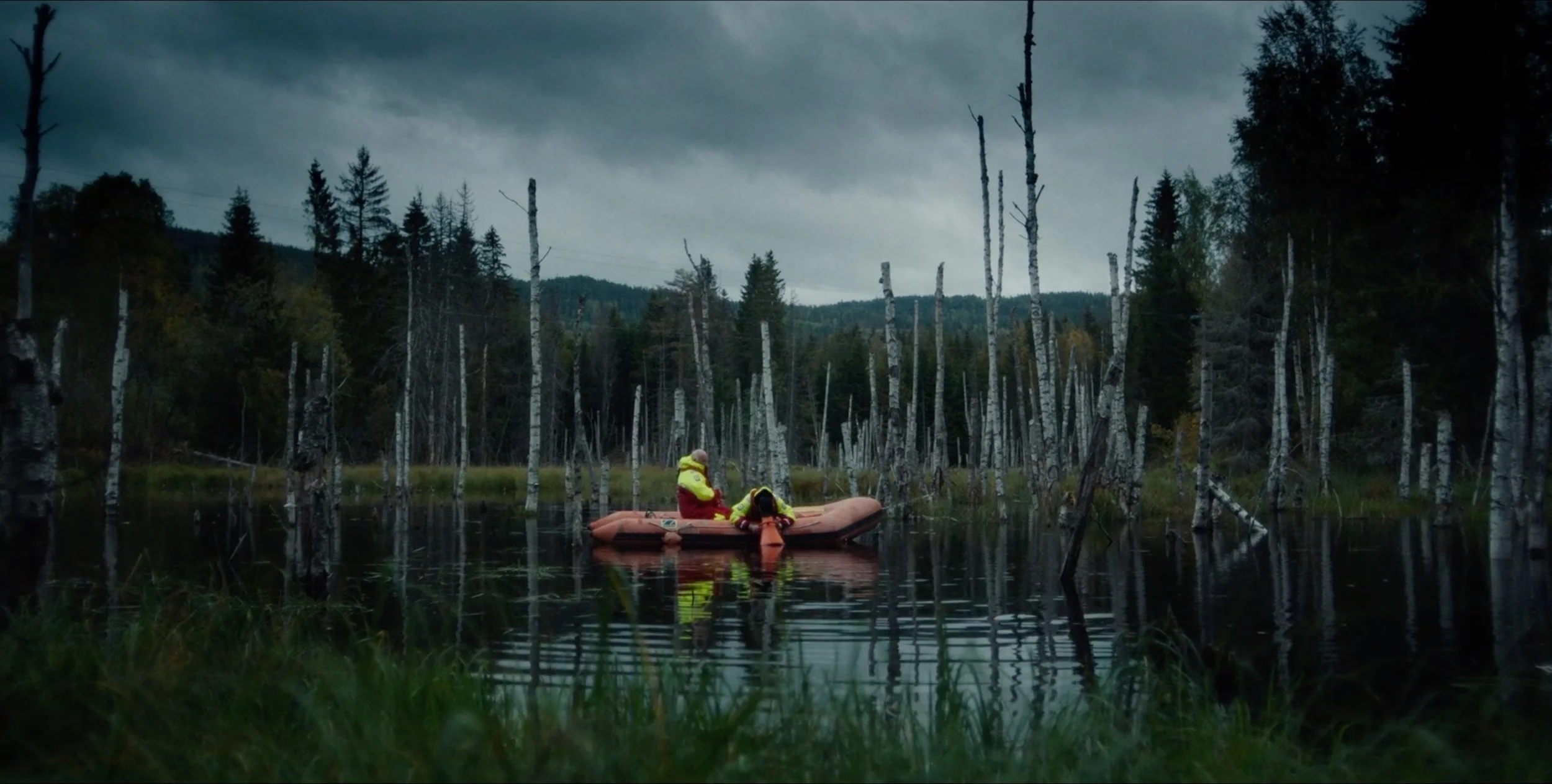 People in a small boat on a dark forest lake in Fenris, cinematography by Johan-Fredrik Bødtker.