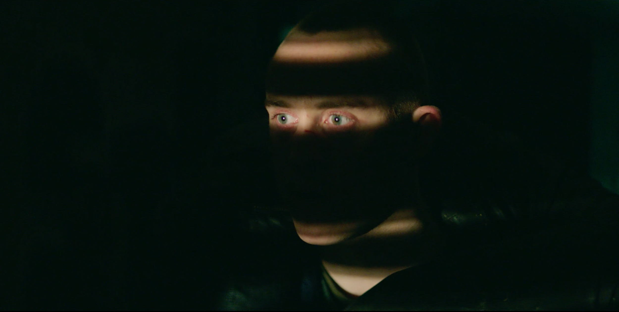 Close-up of a man’s eyes emerging from darkness in Valkyrien, cinematography by Johan-Fredrik Bødtker.