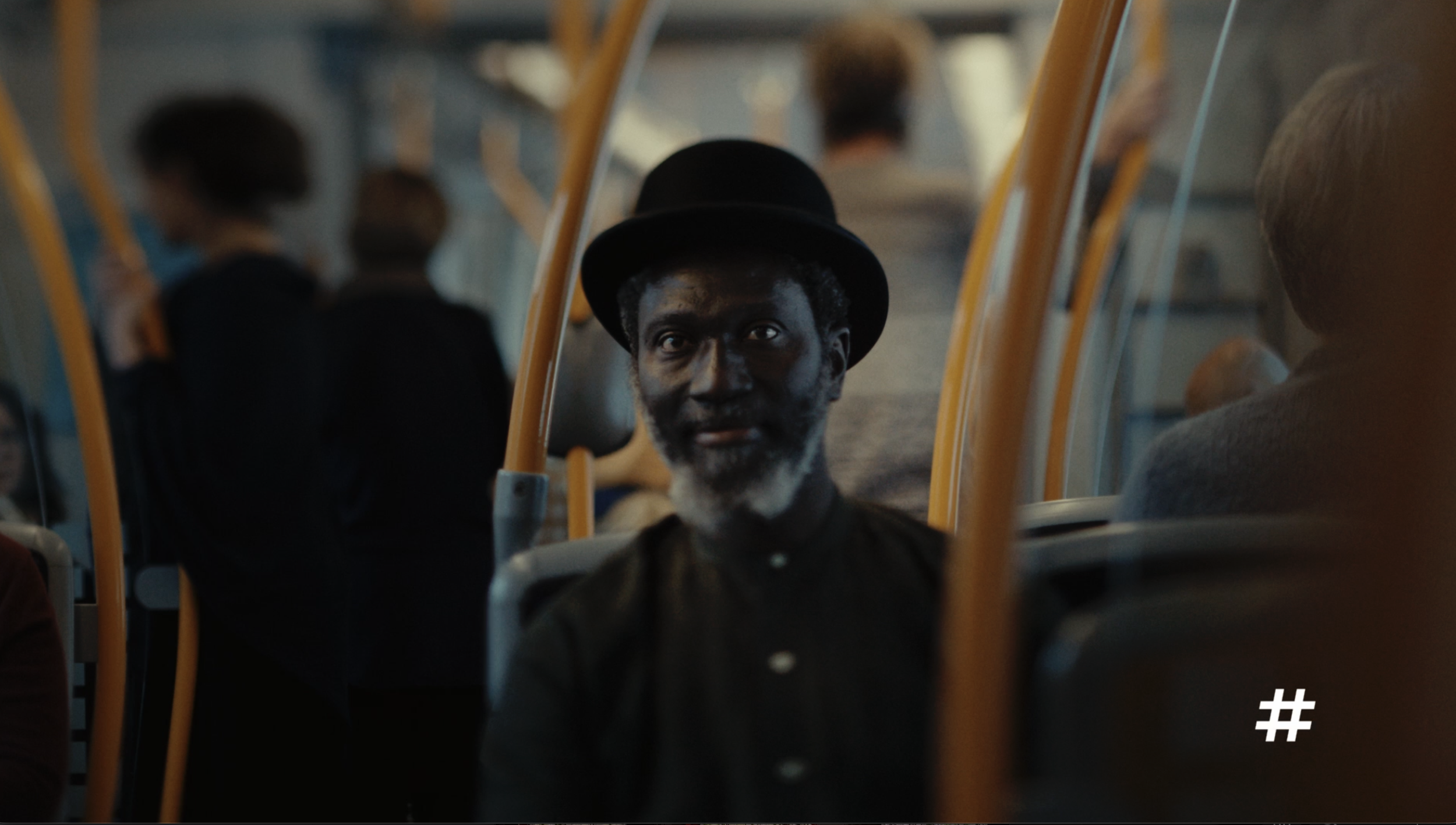 Man wearing a bowler hat seated on a bus in a Ruter commercial, cinematography by Johan-Fredrik Bødtker.