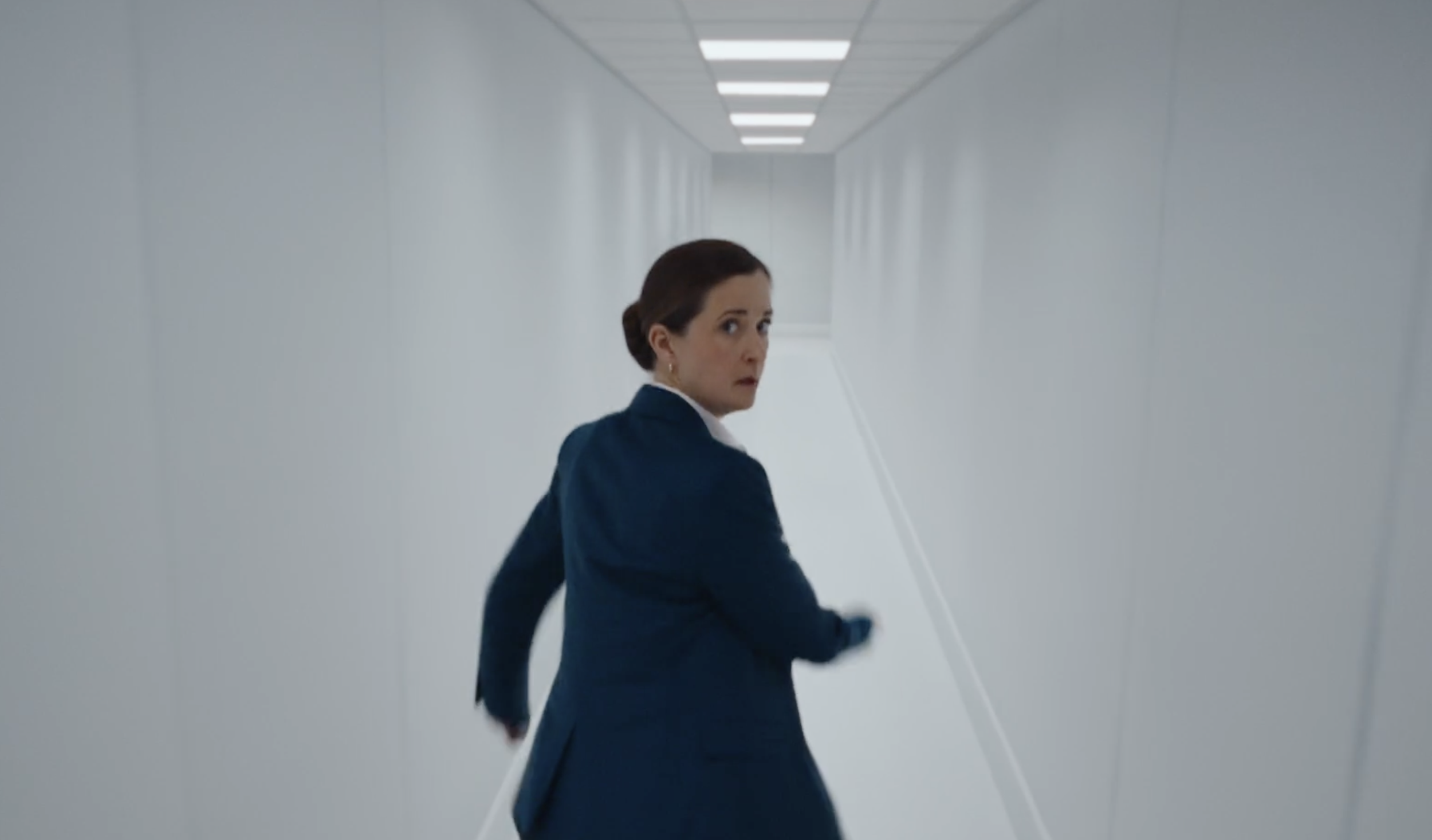 Woman in a blue suit running through a white office corridor in a PowerOffice commercial, cinematography by Johan-Fredrik Bødtker.