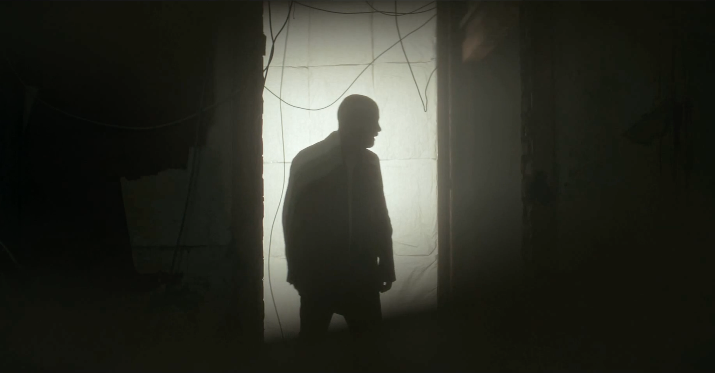 Silhouetted man standing in a doorway in Occupied, cinematography by Johan-Fredrik Bødtker.