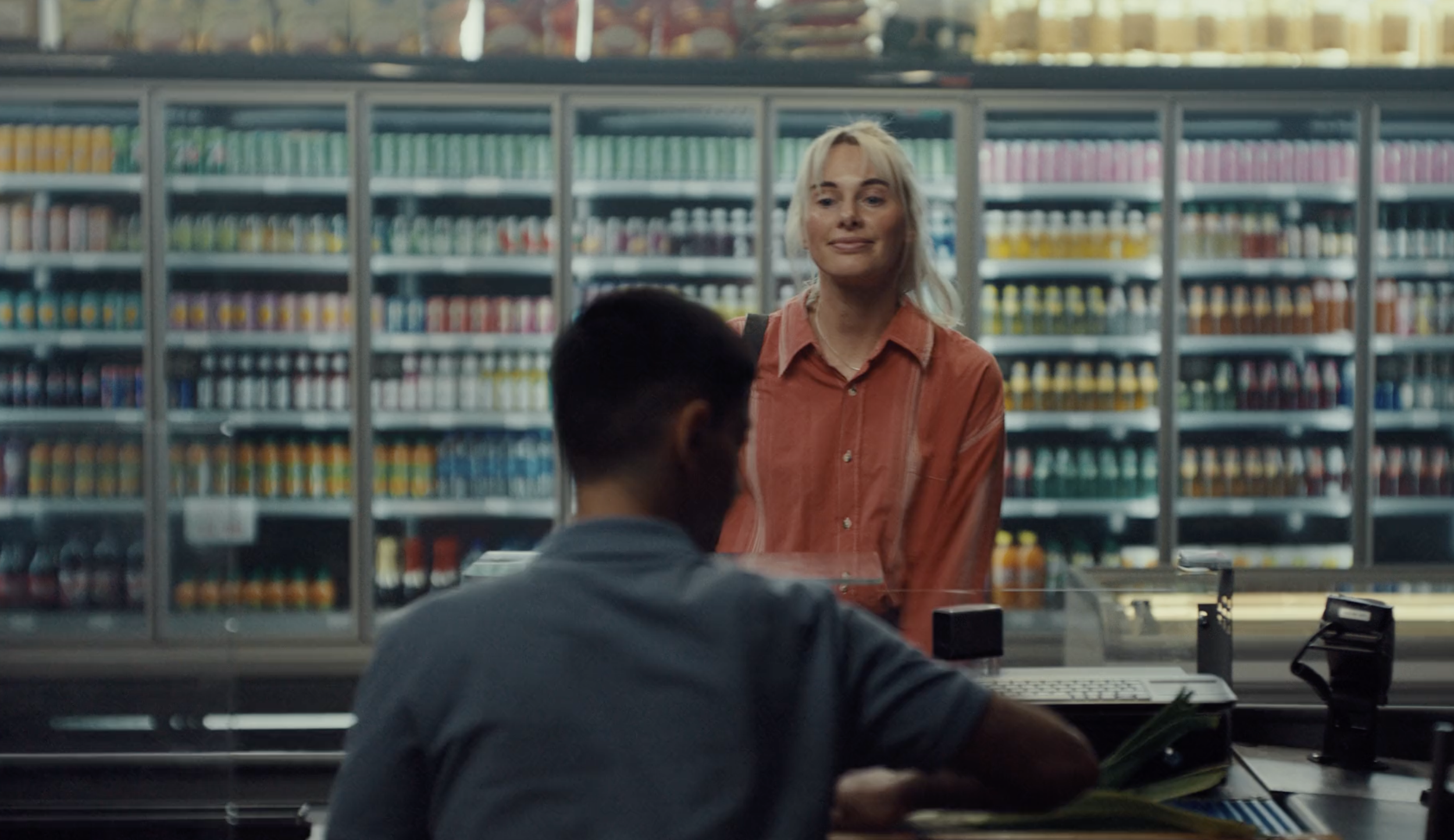 Woman behind a convenience store counter facing a customer in a Vend / Blokket commercial, cinematography by Johan-Fredrik Bødtker.