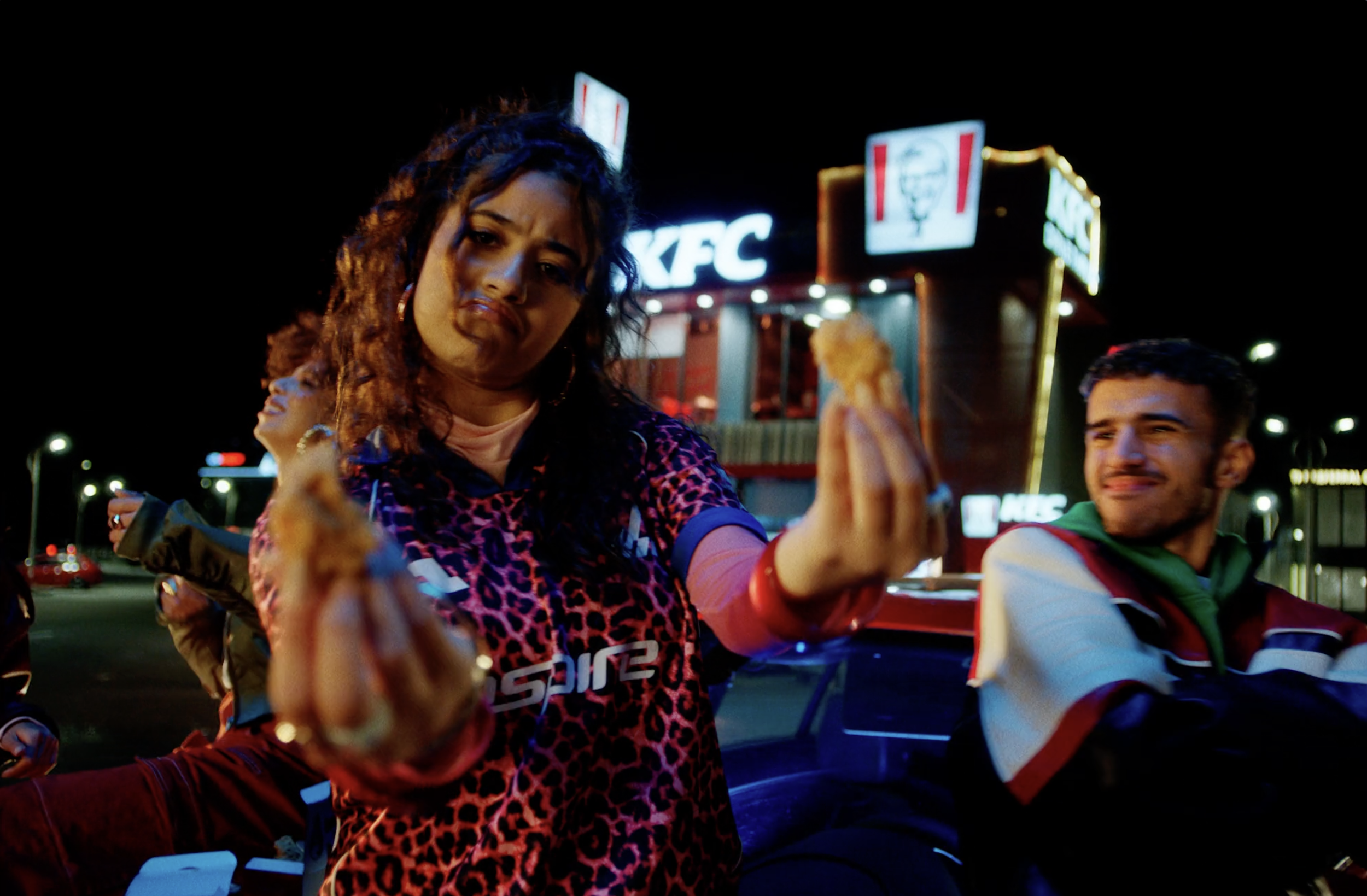 Woman holding KFC chicken outside a restaurant at night in a commercial still, cinematography by Johan-Fredrik Bødtker.