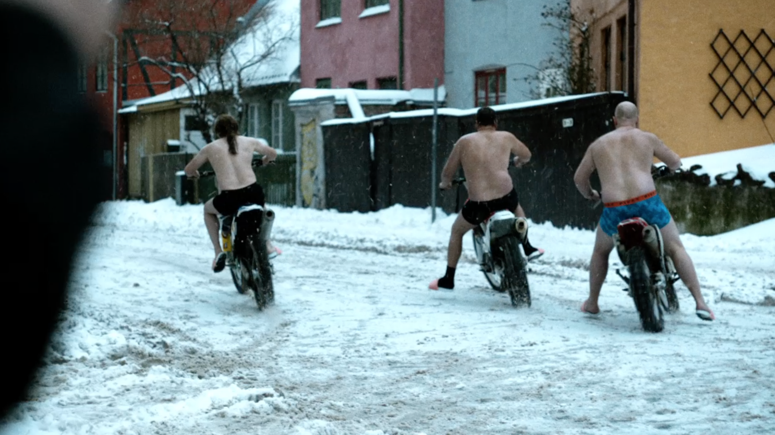 Three bare chested men riding motorcycles on a snowy street in Lilyhammer, cinematography by Johan-Fredrik Bødtker.
