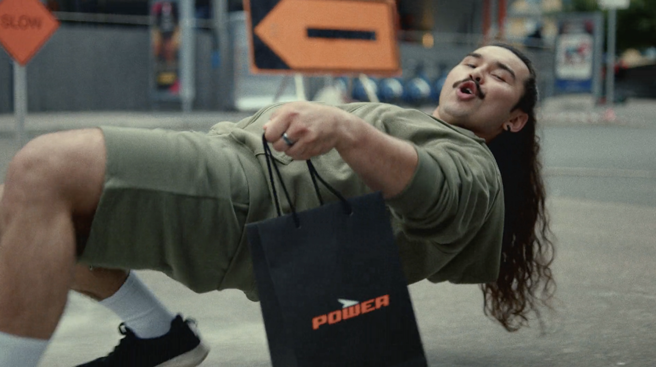 Man holding a Power shopping bag on a city street in a commercial still, cinematography by Johan-Fredrik Bødtker.
