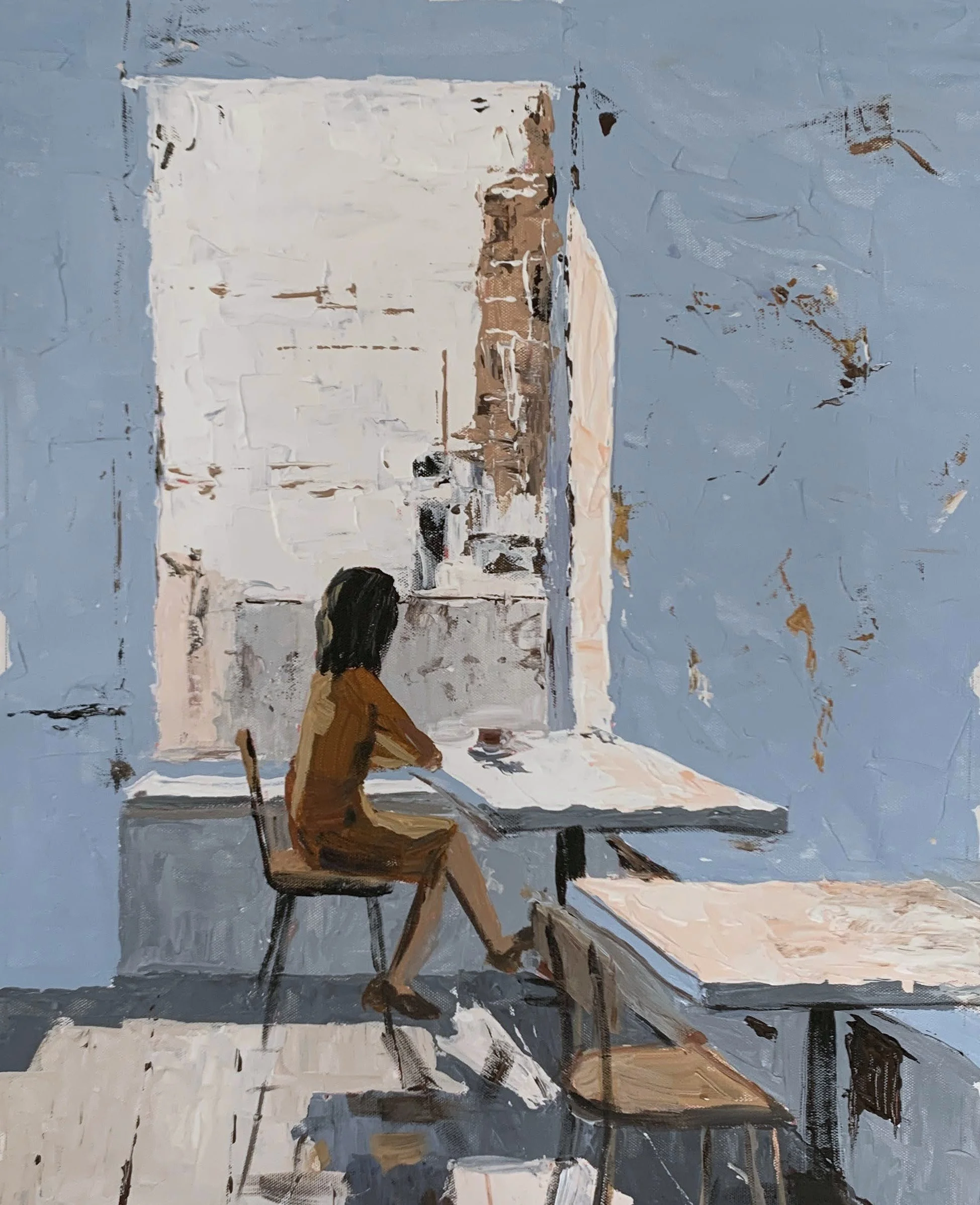 Vita Schagen  Dark-haired woman seated alone at a small café table in a blue-grey interior