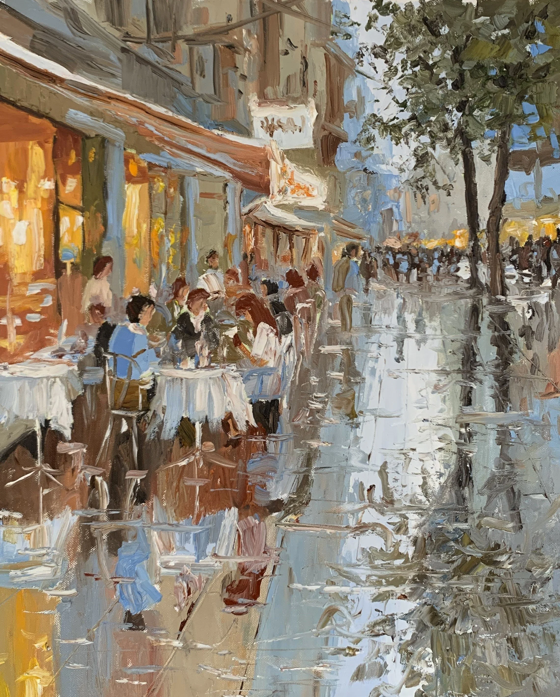 Busy café street with outdoor tables, pedestrians pale reflections on wet pavements
