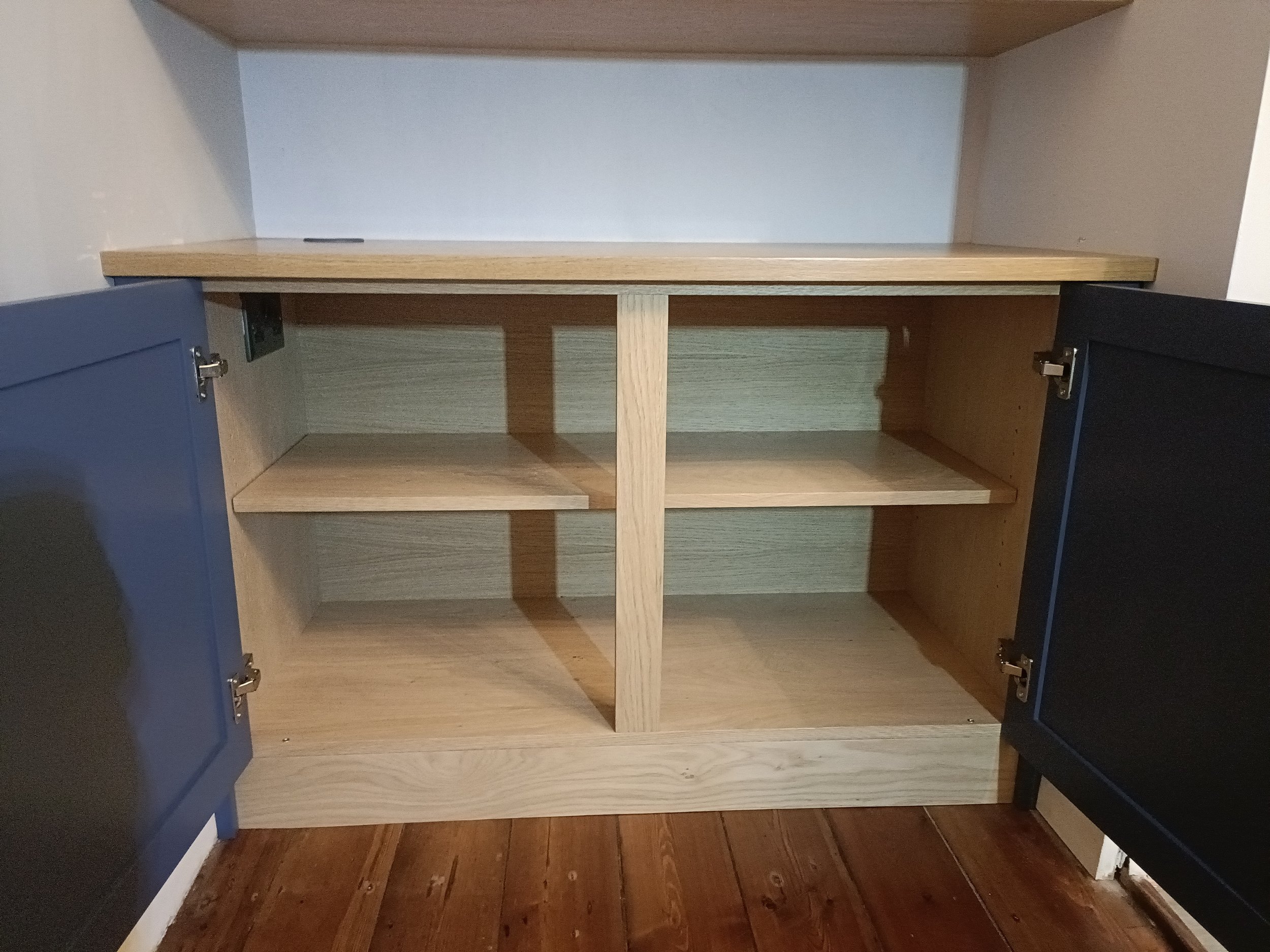 An alcove cabinet with floating shelves above in a mix of painted finish and oak, installed in Gosforth. The oak floating shelves are extra deep and have additional removable 'lifts' at the back to allow the display of a double row of paperback books
