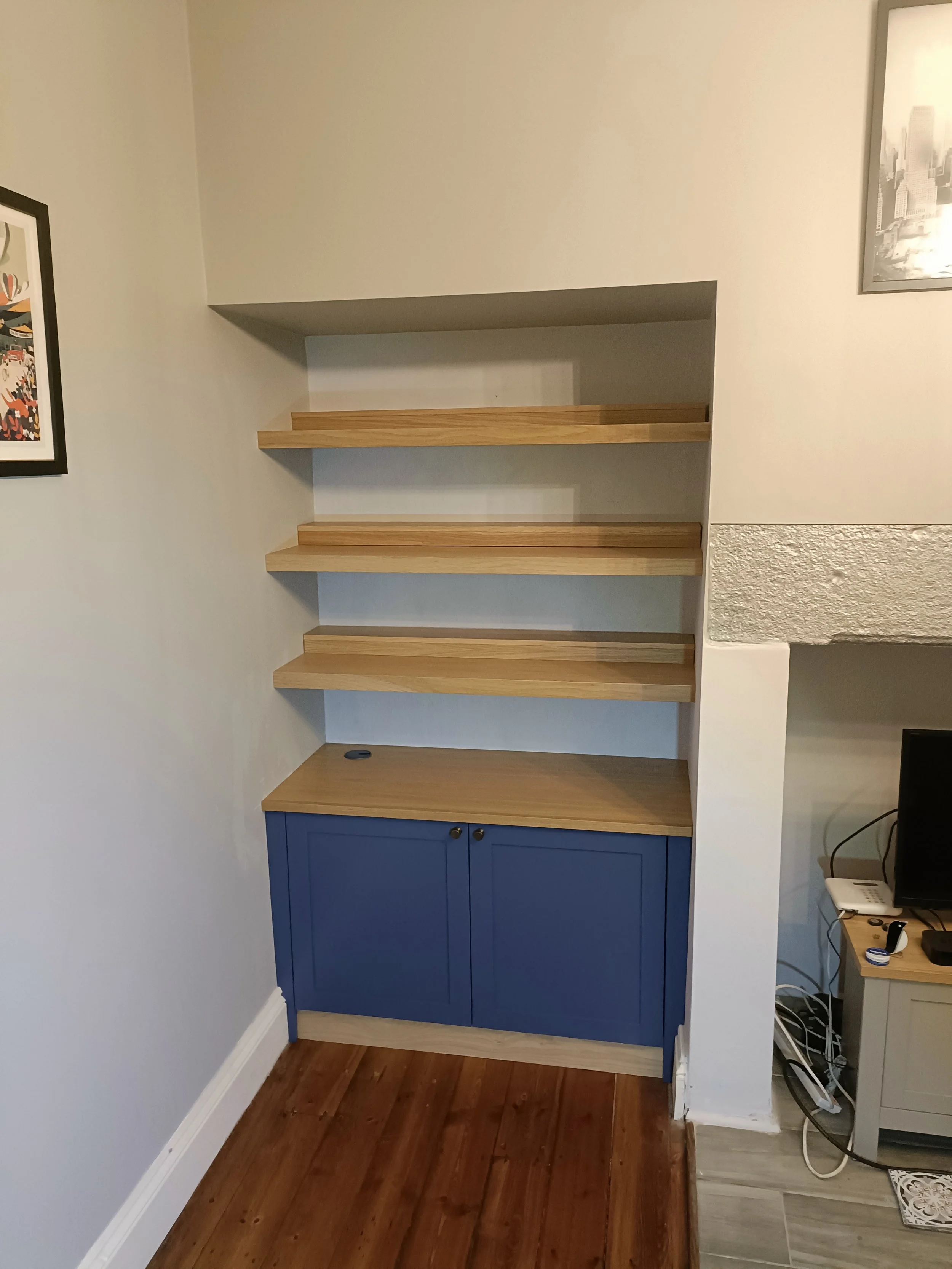 An alcove cabinet with floating shelves above in a mix of painted finish and oak, installed in Gosforth. The oak floating shelves are extra deep and have additional removable 'lifts' at the back to allow the display of a double row of paperback books