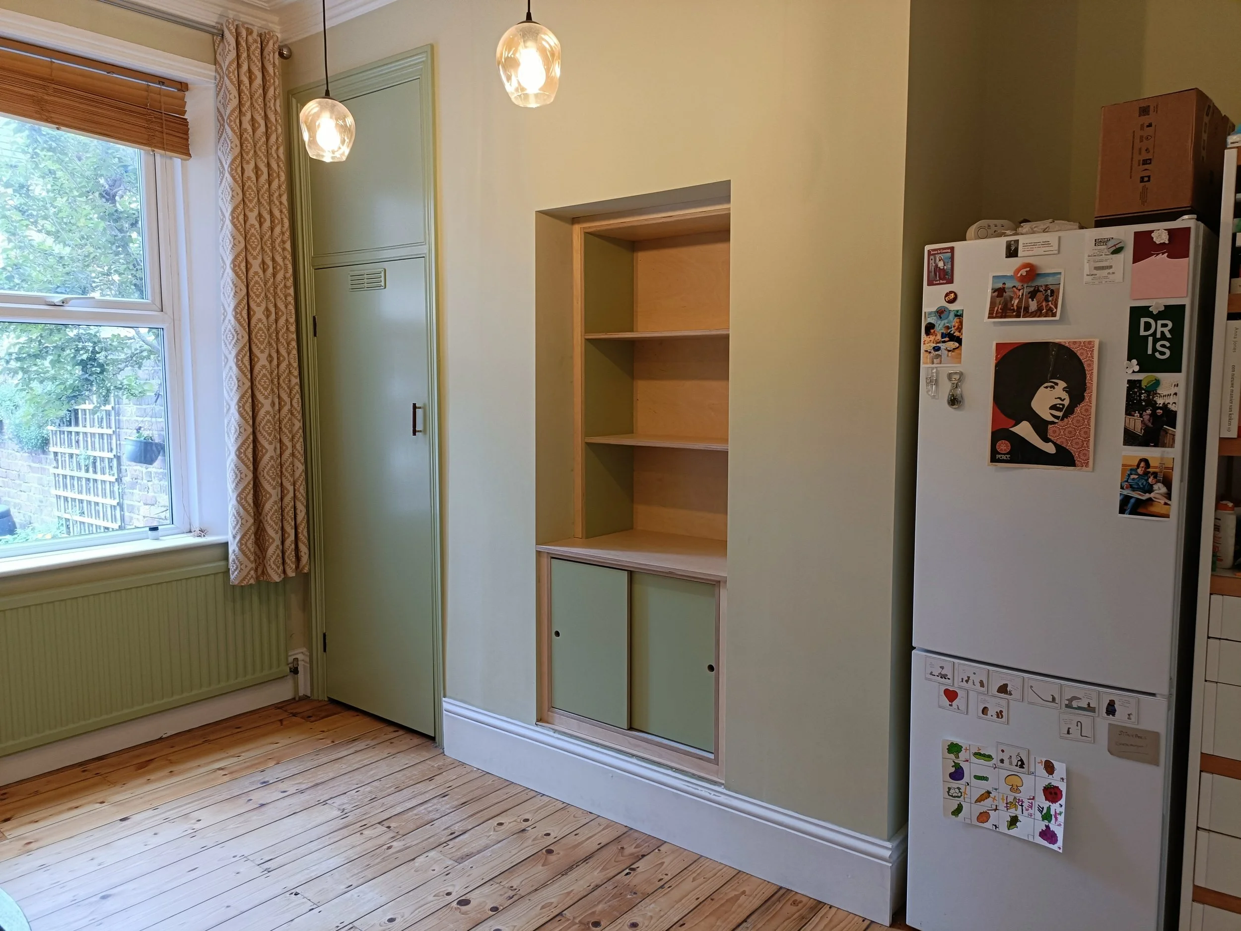 Birch ply unit with painted elements and sliding doors installed into a small fireplace alcove in Heaton. 