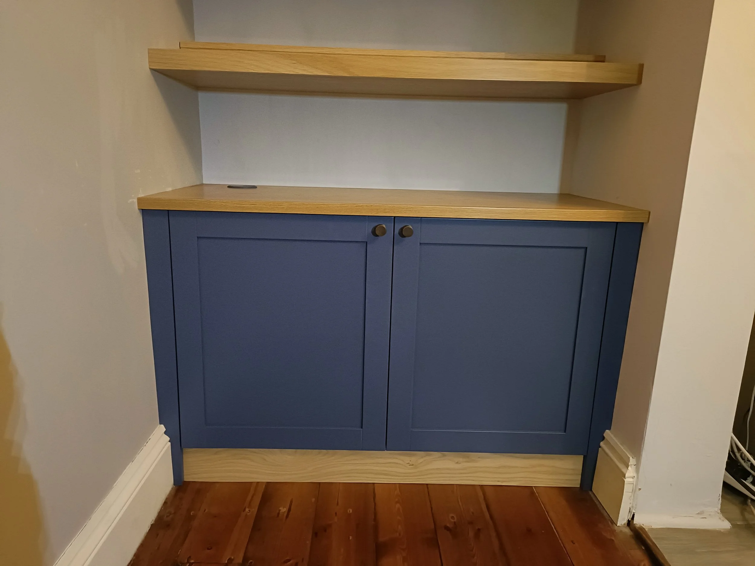 An alcove cabinet with floating shelves above in a mix of painted finish and oak, installed in Gosforth. The oak floating shelves are extra deep and have additional removable 'lifts' at the back to allow the display of a double row of paperback books