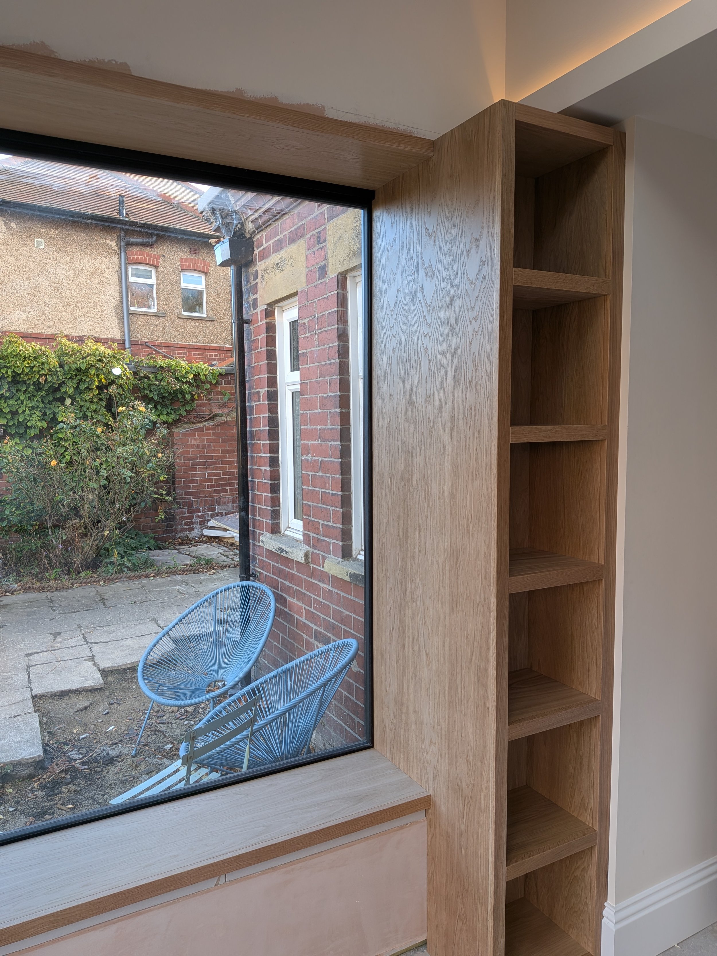 Oak window seat and surround with integrated bookcase installed in a new kitchen extension in Tynemouth. 