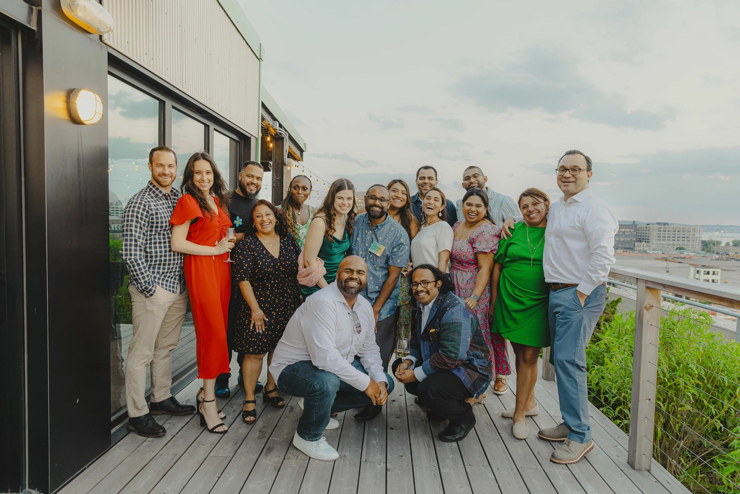Image of a group of fancily dressed adults posing together outdoors at an event.