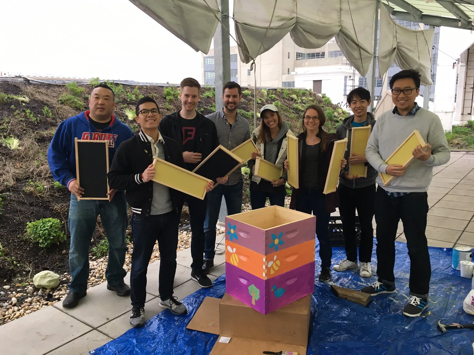 Volunteers excitedly pose with the decorated bee hive frame