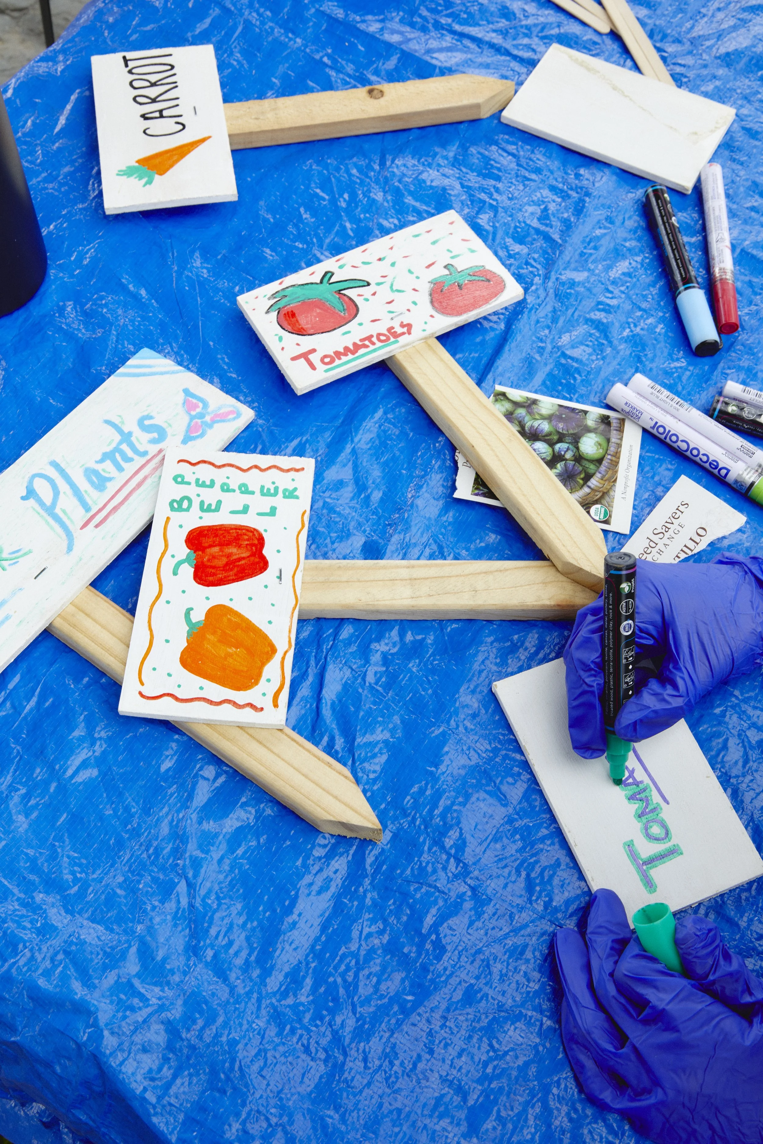 Volunteers designing creative wood plant signages for placement in soil