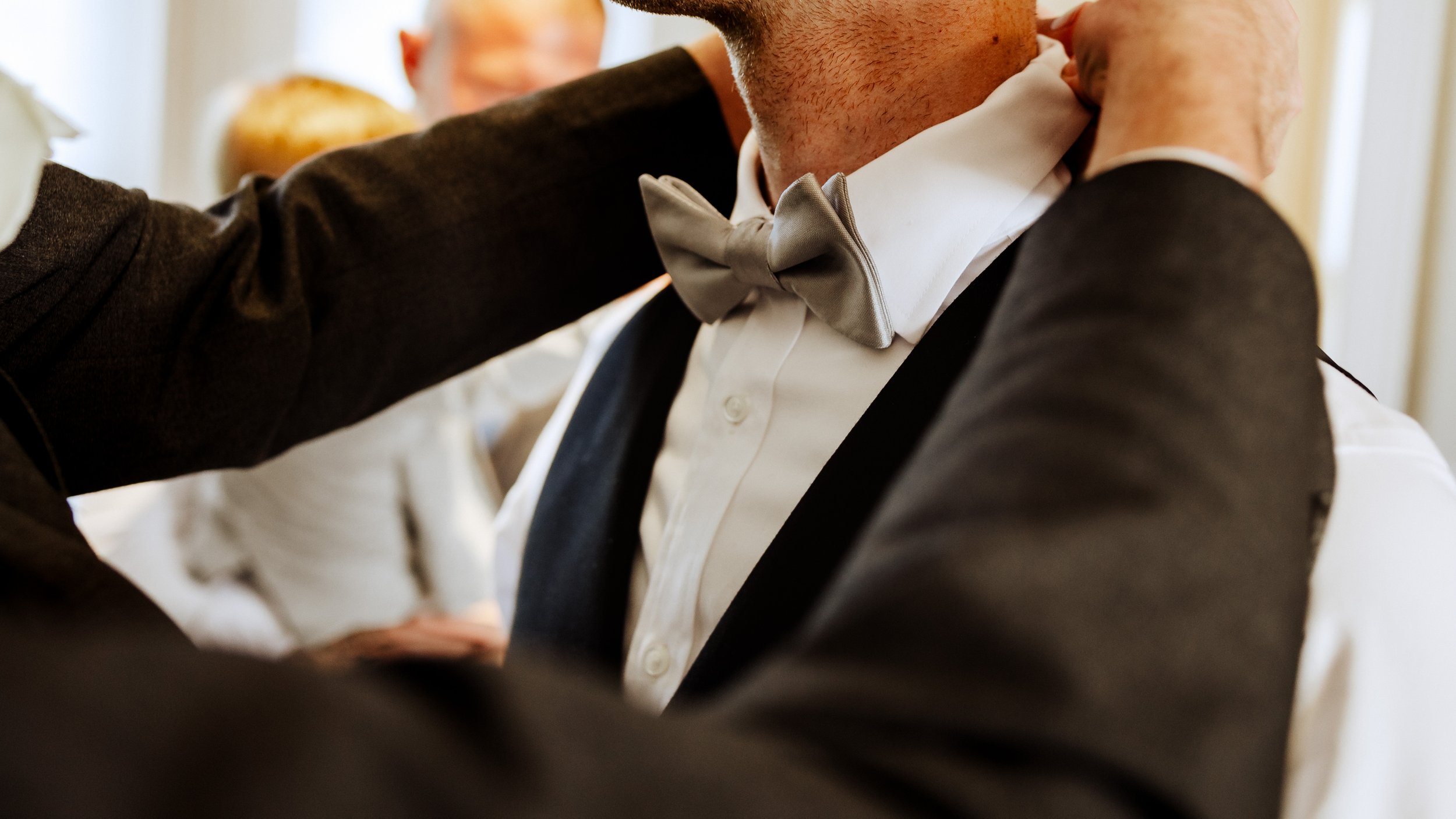 groom’s bowtie getting fixed by best man 