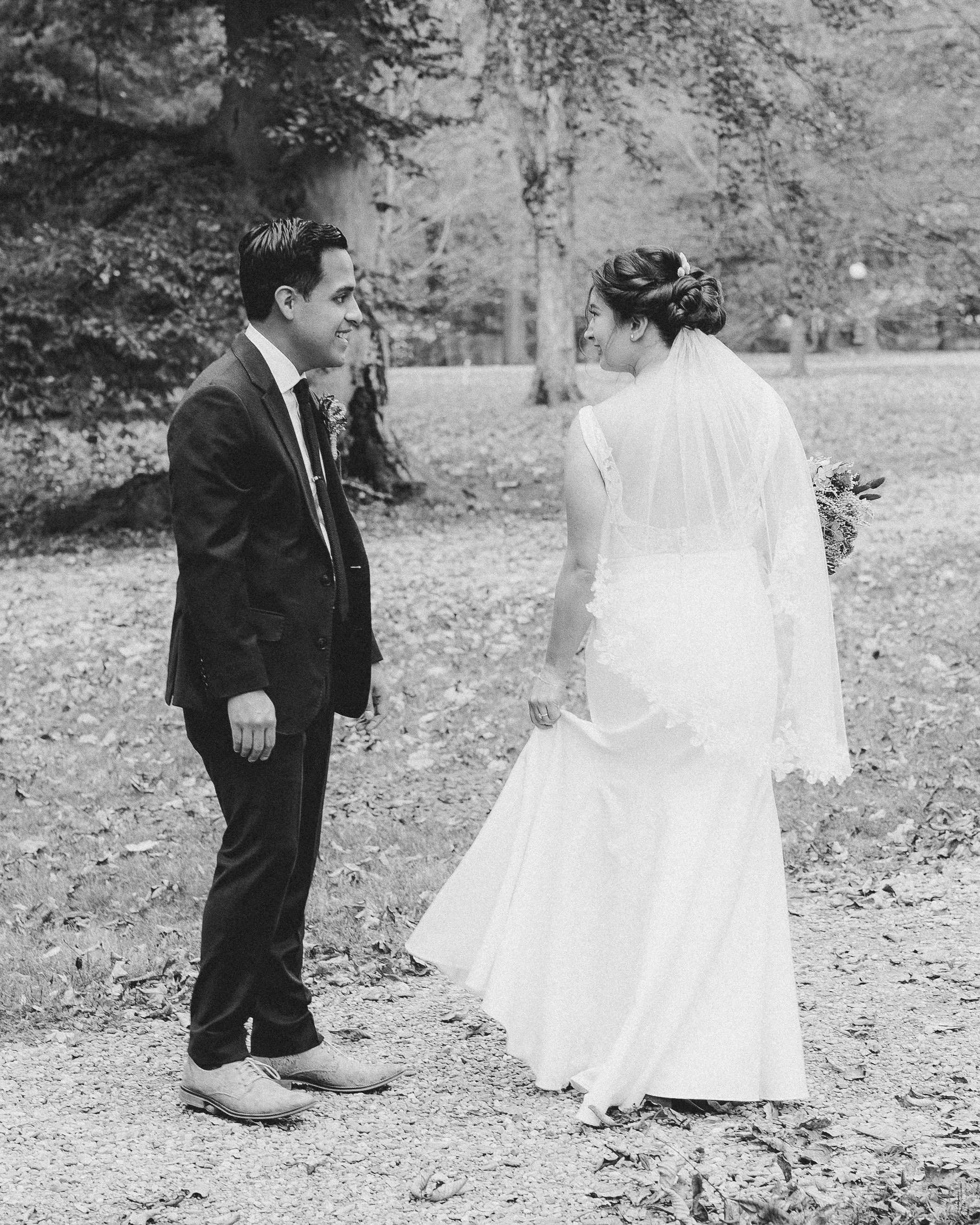 bride holding the bottom of her dress off from the ground and showing the back of her dress to the groom