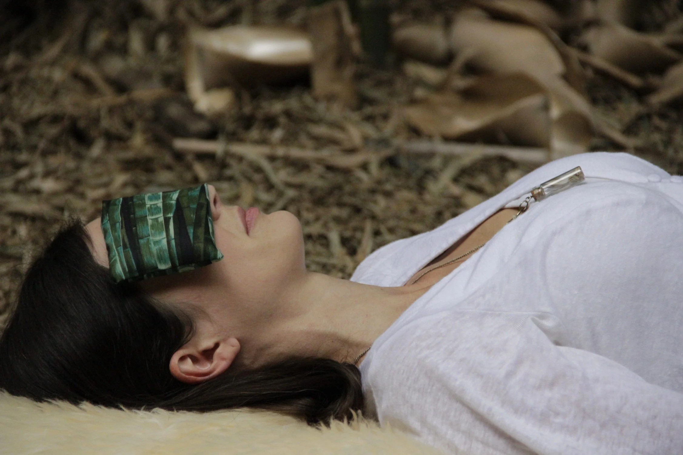 Woman lying int he ground with an eye pillow over her eyes in yoga nidra meditation.