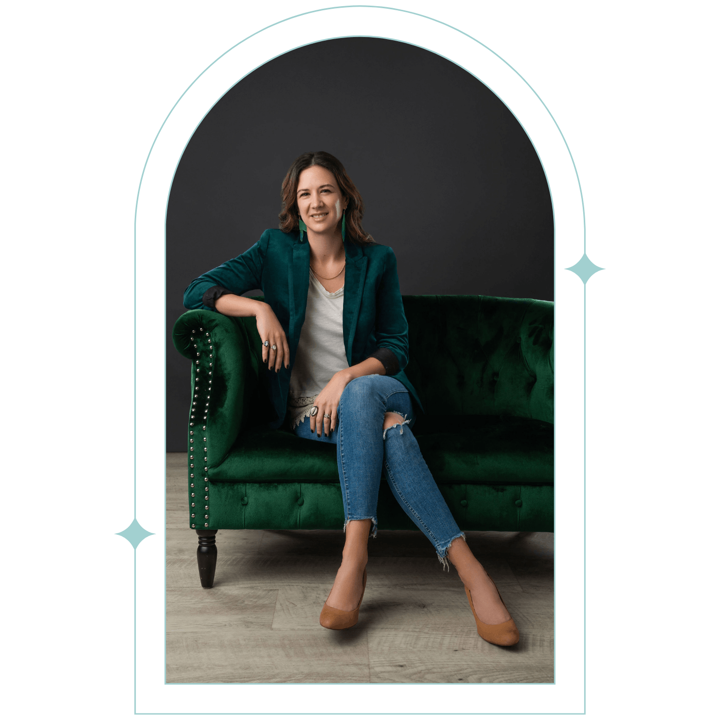 Genevieve Camp smiling and sitting on a green velvet couch.