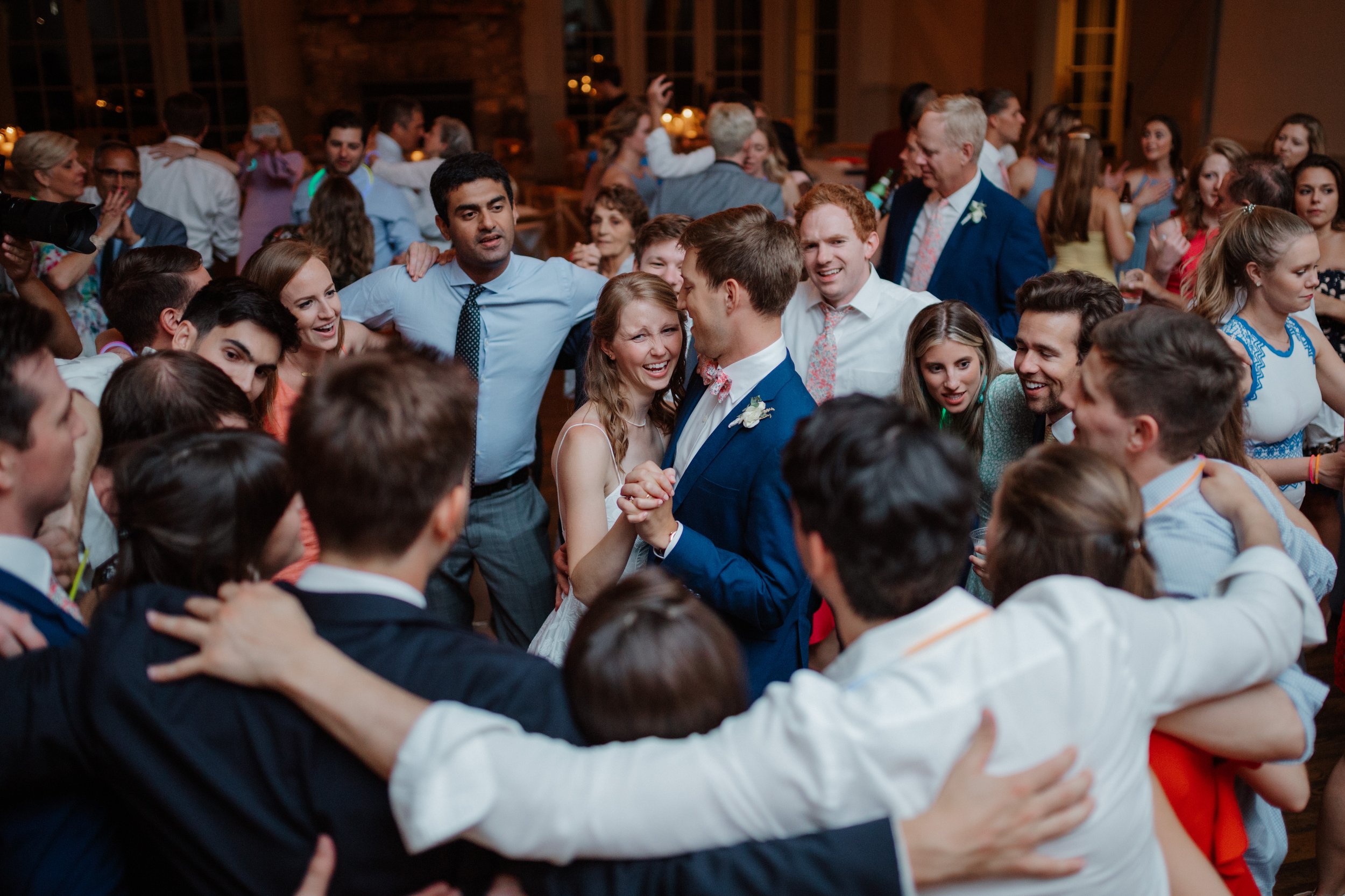 crowd of friends dancing around the bride and groom at a wedding reception
