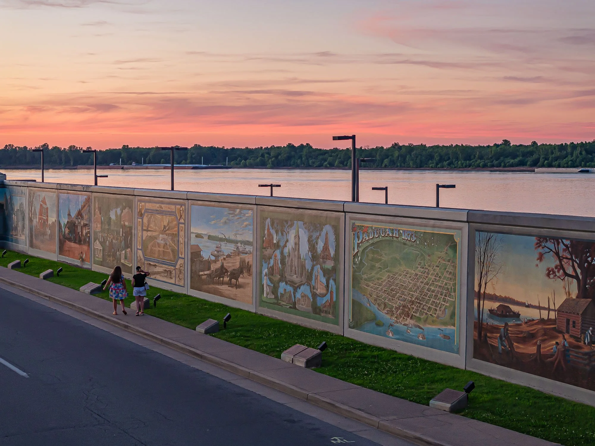 Drone Photography People walking by Riverfront Flood Wall with Art at Sunset