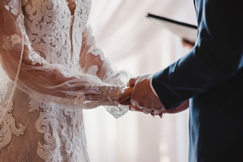 Bride and groom hold hands during wedding ceremony