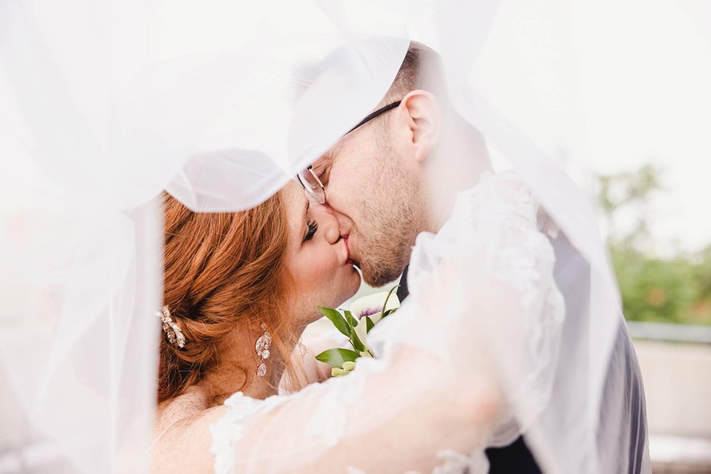 Bride and groom kiss under veil at Warehouse District Wedding