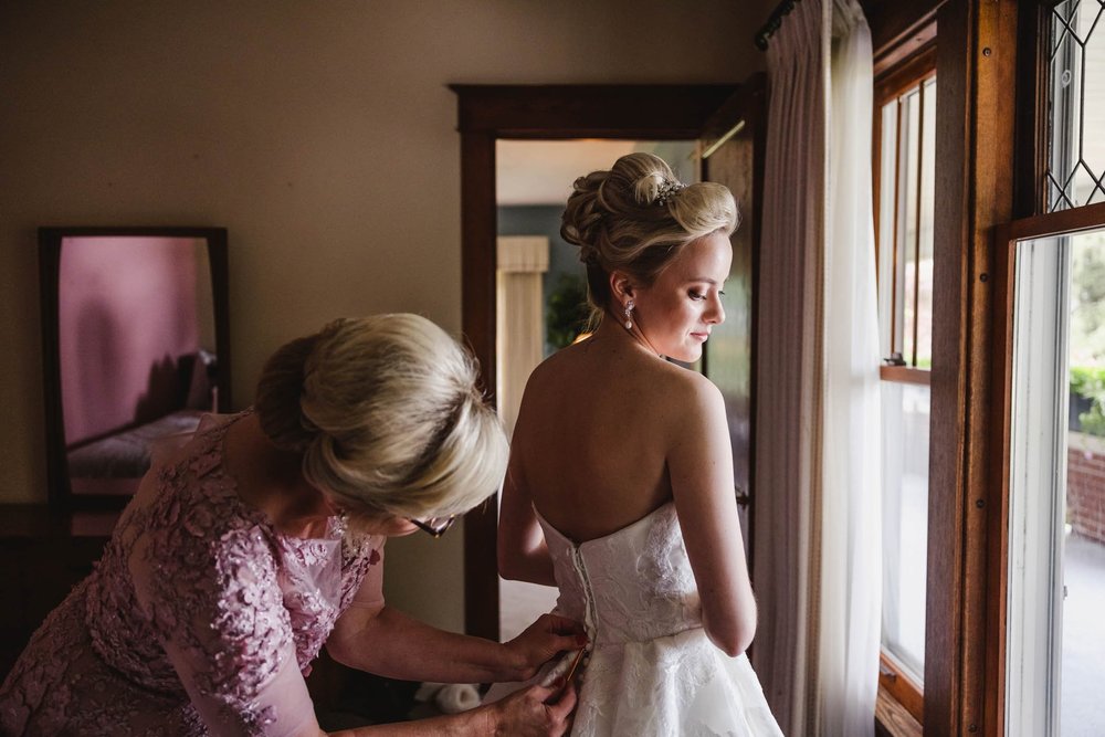 Mother helps bride get dressed
