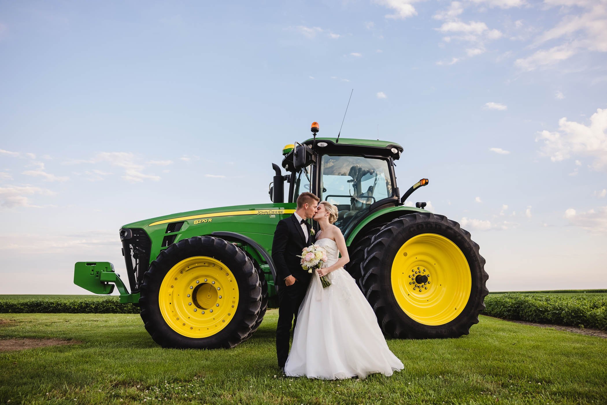 Bride and groom kiss with John Deere tractor